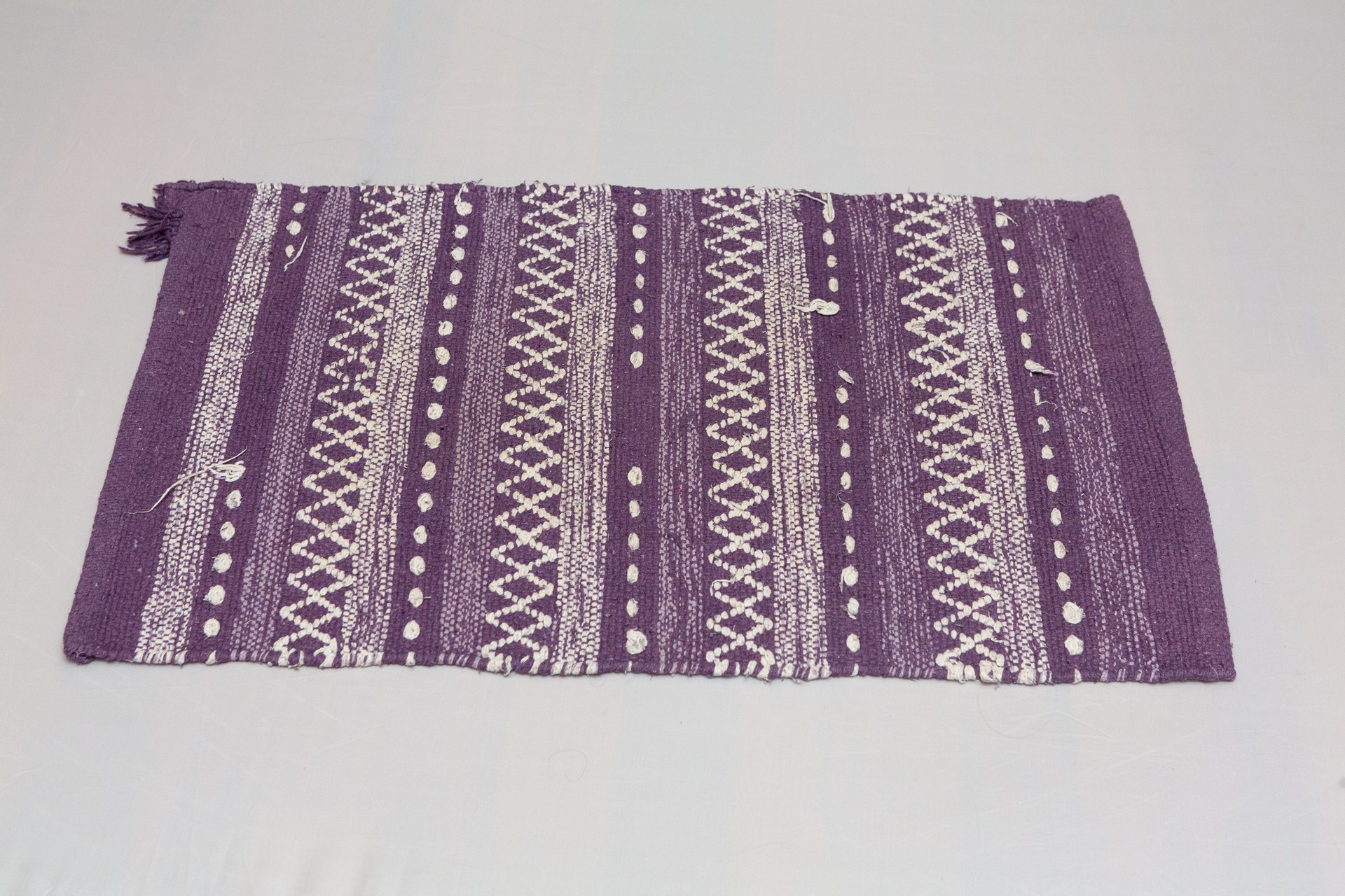 Purple woven rug with white tribal pattern displaying weaving technique